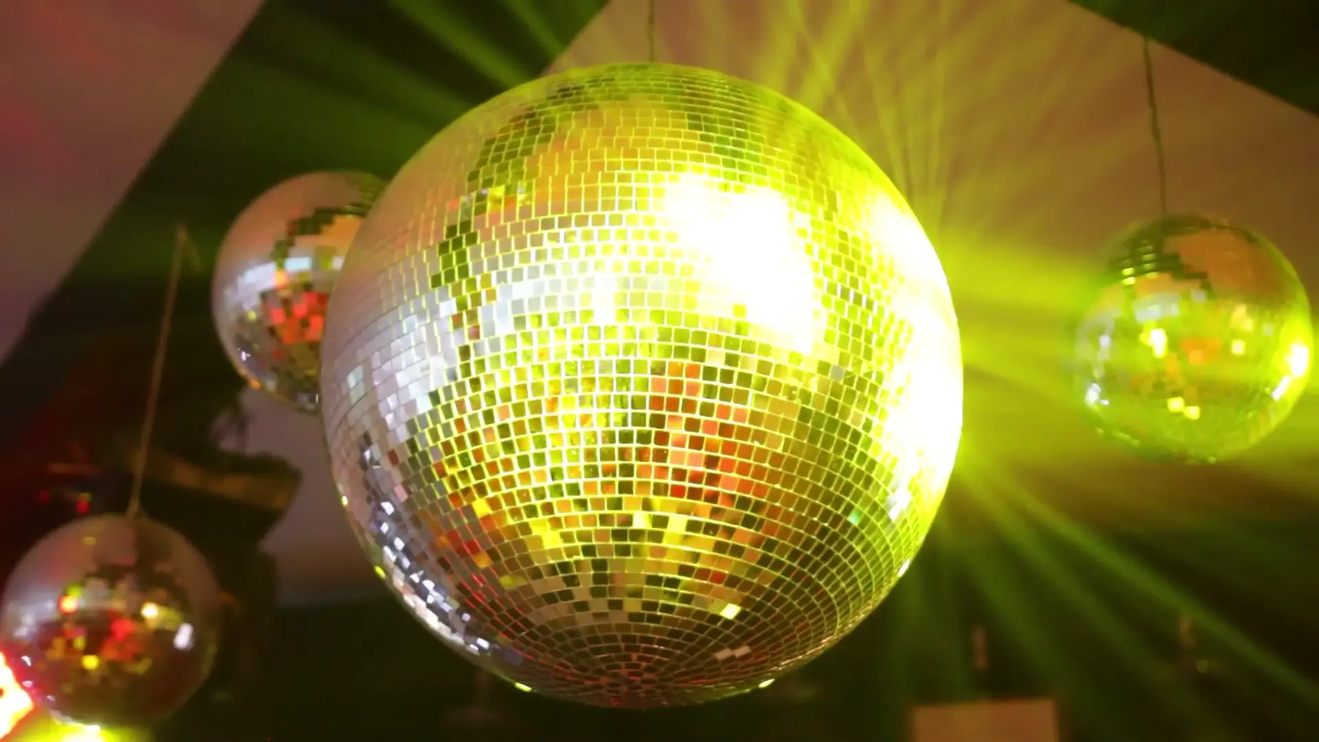 Gold mirror balls hanging from a dark ceiling, scattering warm light across the room